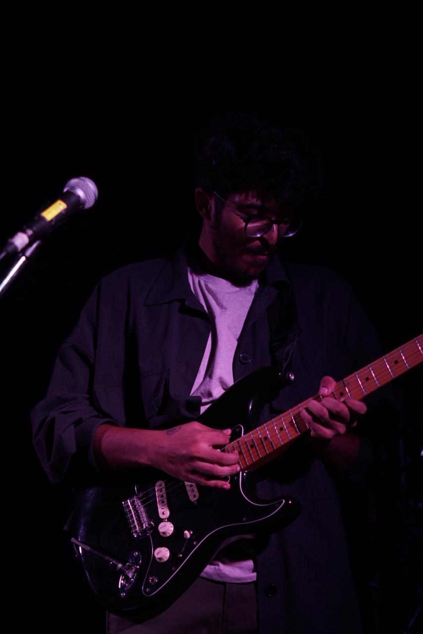 Sanjith playing acoustic guitar on stage